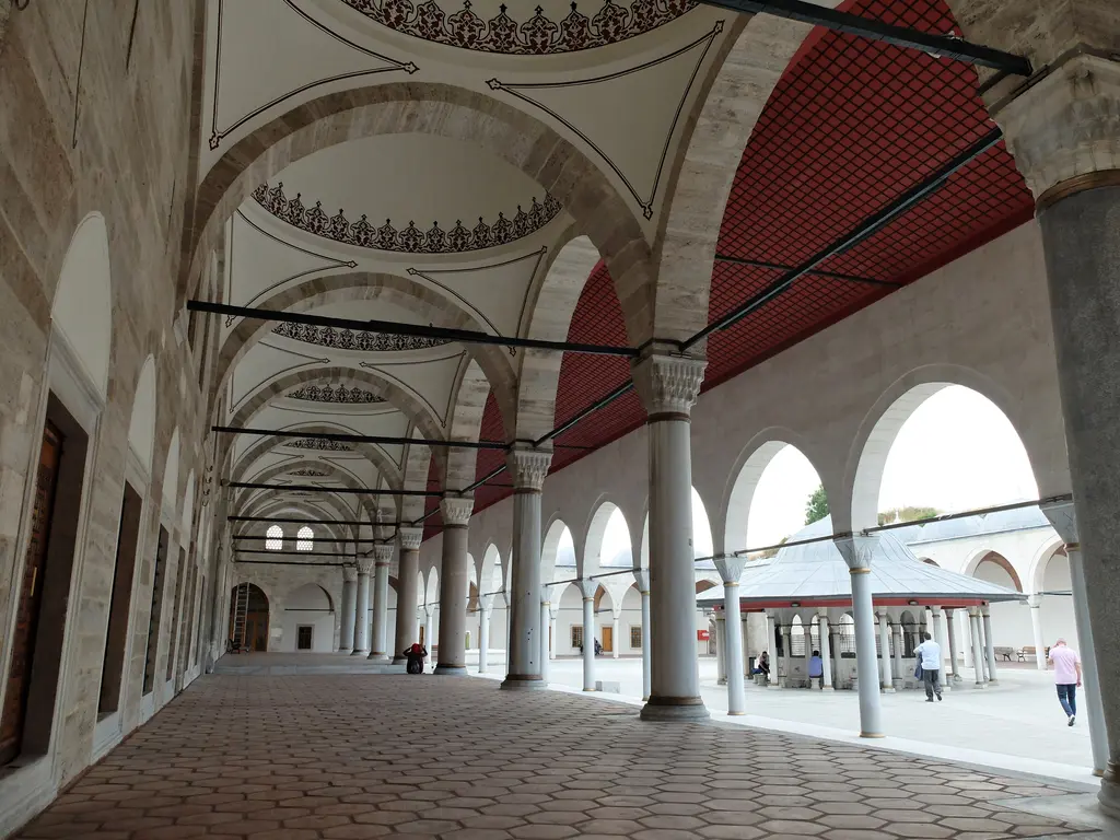 Mihrimah Sultan Camii'nin son cemaat yeri; çift sıra sütun ve kemerler, kırmızı boyalı ahşap tavan, kırmızı zemin ve arkada cami kapısı.