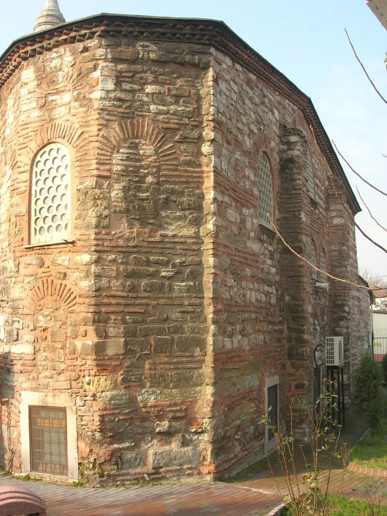 Atik Mustafa Paşa Camii'nin köşesinde çok yüzlü tuğla duvar; almaşık taş ve tuğla sıraları, kemerli şebekeli pencere, dişli tuğla saçak ve dipte demir parmaklıklı pencere.