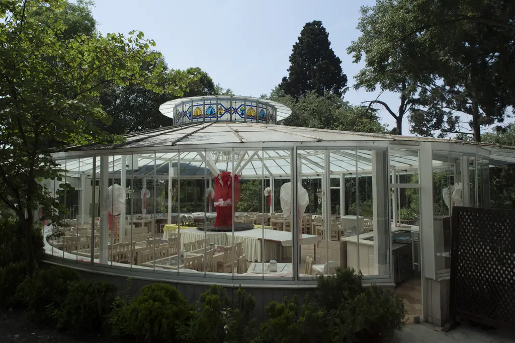 Yıldız Parkı'nda camlı bir kafe; yuvarlak cam duvarlı yapı, içeride masalar ve sandalyeler, üstte renkli camlı fener.