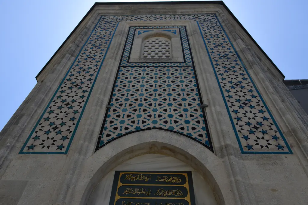 Mahmut Paşa Türbesi'nin çini kaplı cephesi alttan; yıldız geçmeli firuze ve lacivert desen, sivri kemerli pencere ve altta yazı panosu.