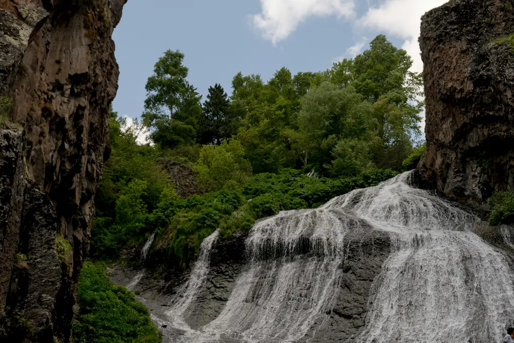 Jermuk'ta iki kaya duvarının arasından geniş bir yelpaze hâlinde yayılarak akan şelale; kayanın üzerinde ince tabakalar hâlinde dağılan su, çevresinde yoğun yeşil orman.