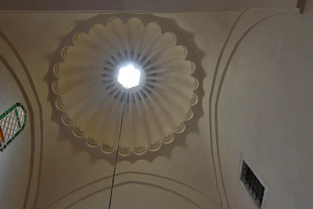 Mahmut Paşa Camii'nin iç giriş mekânında dilimli kubbe; ortada ışık alan tepe penceresi, krem rengi sıva ve köşede küçük bir pencere.