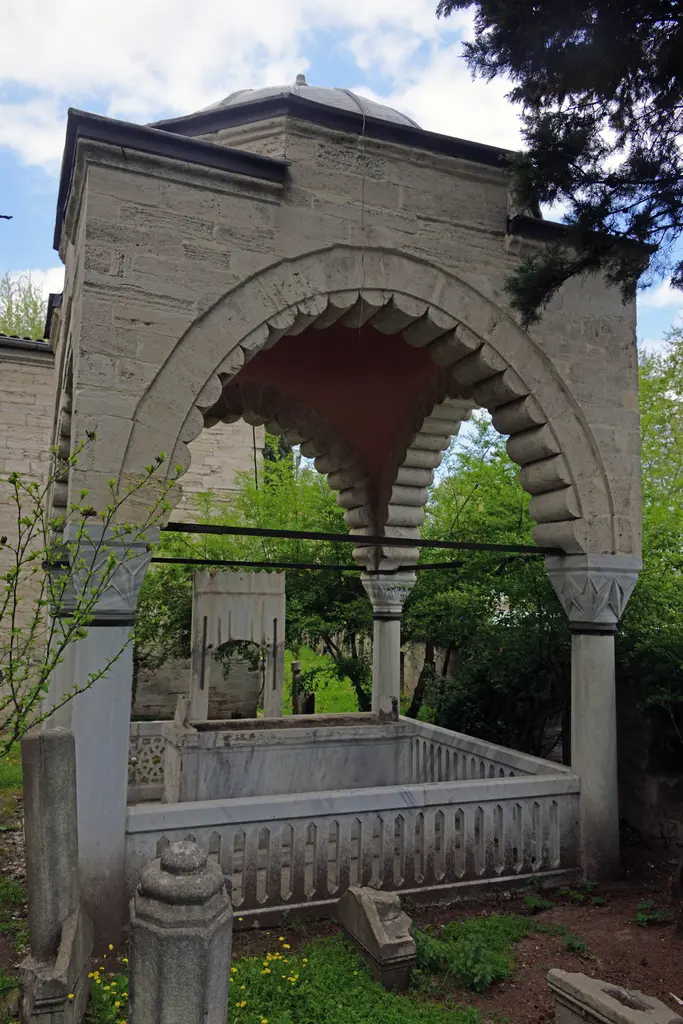 Defterdar Mahmud Çelebi Türbesi; kesme taş kemerler, kurşun kaplı küçük kubbe, sütunlar, mermer korkuluk ve selviler.