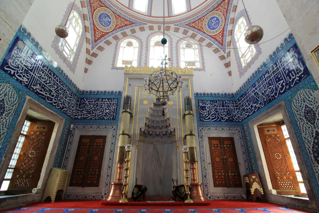Atik Valide Camii'nin mihrabı; mermer mihrap, iki yanda büyük şamdanlar, duvarlarda mavi çini yazılar.