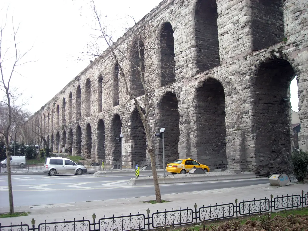 Bozdoğan Kemeri yandan alçak açıdan; iki katlı kemer dizisi derinlemesine kaçıyor, en yakın ayaklar kalın ve kaba taş, önde yapraksız çınarlar ile demir korkuluk.