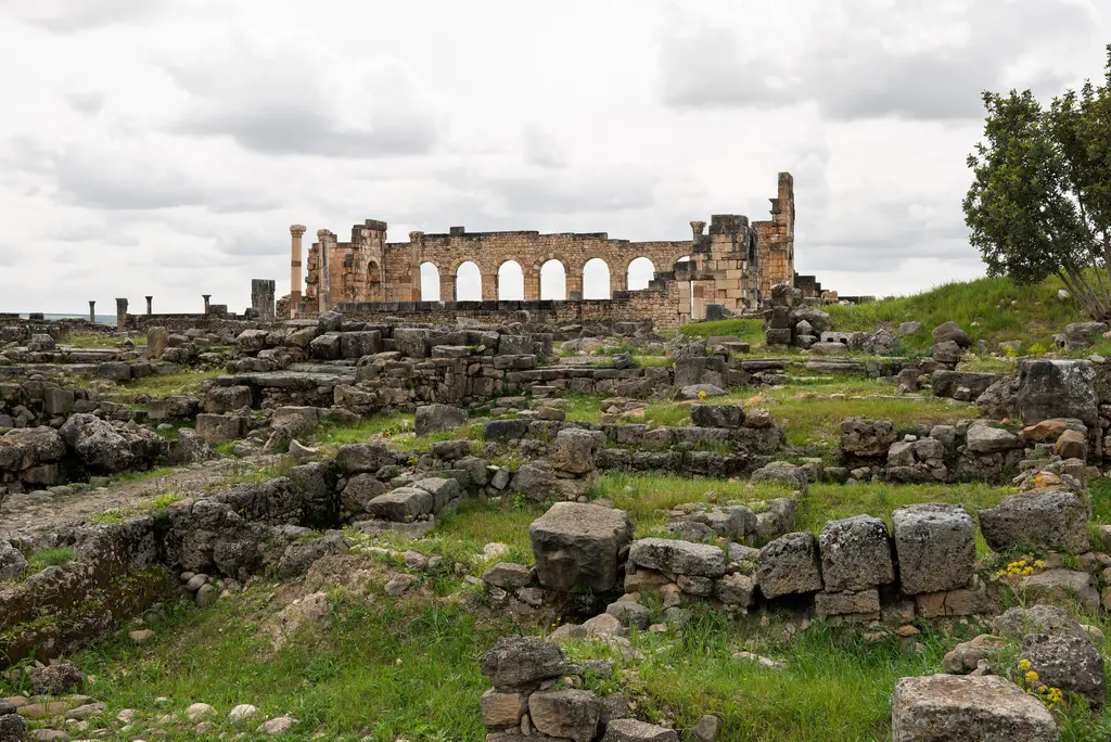 Volubilis Roma kenti kalıntıları; ayakta duran sütunlar, zafer takı ve ardındaki ova.