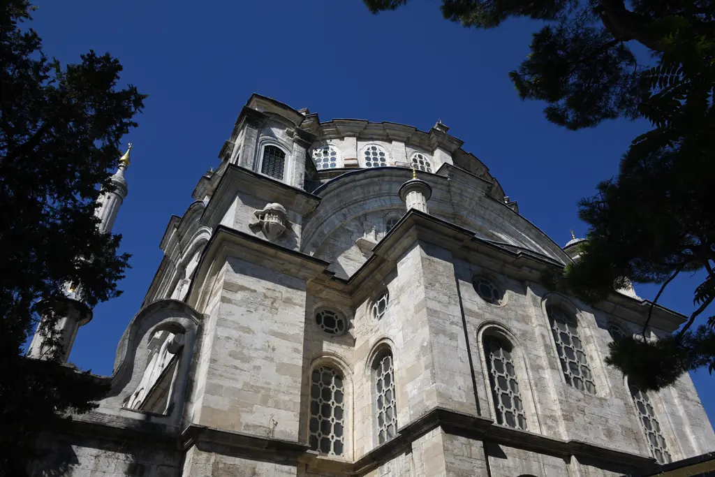Selimiye Camii'nin köşesi; aşağıdan bakışla taş duvar, kemerli pencereler ve süslü ağırlık kulesi.