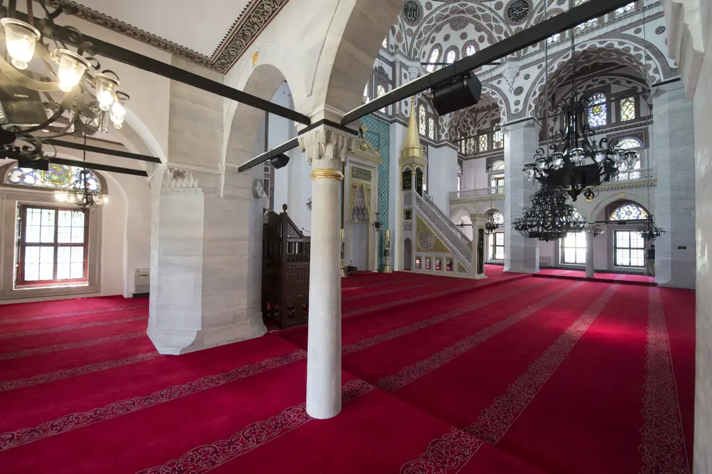 Yeni Valide Camii'nin içi; mermer sütun, kırmızı halı, beyaz duvarlar, pencereler ve arkada minber.