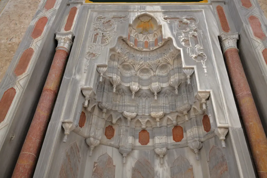 Ortaköy Camii'nin mihrabı; beyaz mermerde kademeli niş, mukarnaslı kavsara, kabartma bitki motifleri ve pembe taş çerçeve.