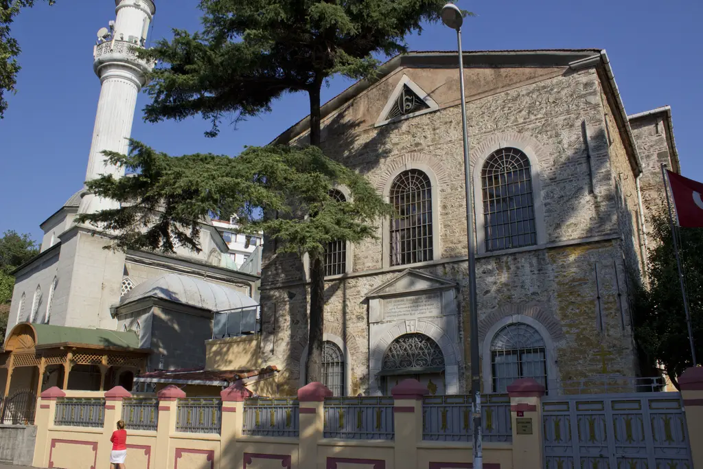 Kuzguncuk'ta Surp Krikor Lusavoriç Kilisesi ve Kuzguncuk Camii; taş kilise cephesi, yanında minare ve önde bahçe duvarı.