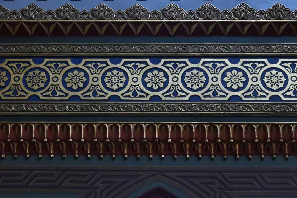 Yıldız Hamidiye Camii'nde bezeme kuşağı; lacivert zemin üzerinde altın rozetler, üstte kıvrımlı saçak ve altta kırmızı dilimler.