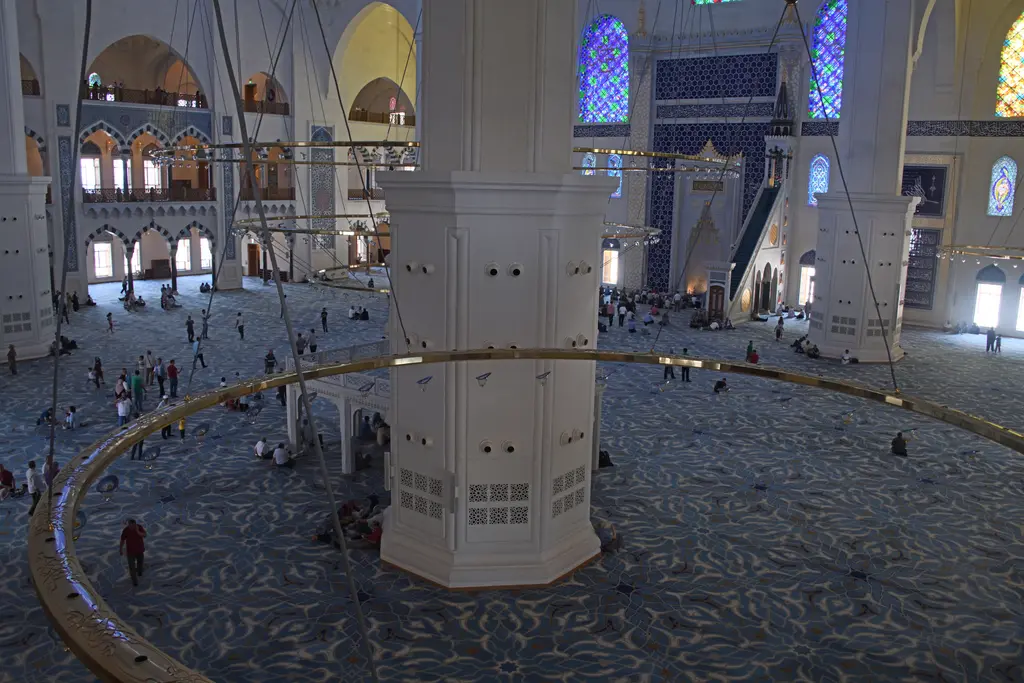 Büyük Çamlıca Camii'nin içi; üst kattan bakışta halılı zemin, halka avize, kalın paye ve namaz kılanlar.