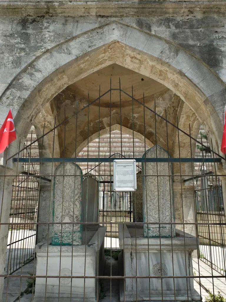 Şirmerd Çavuş Türbesi'nin içi; sivri kemerin altında demir parmaklık, mermer kaideler üstünde işlemeli iki mezar taşı ve bilgi levhası.