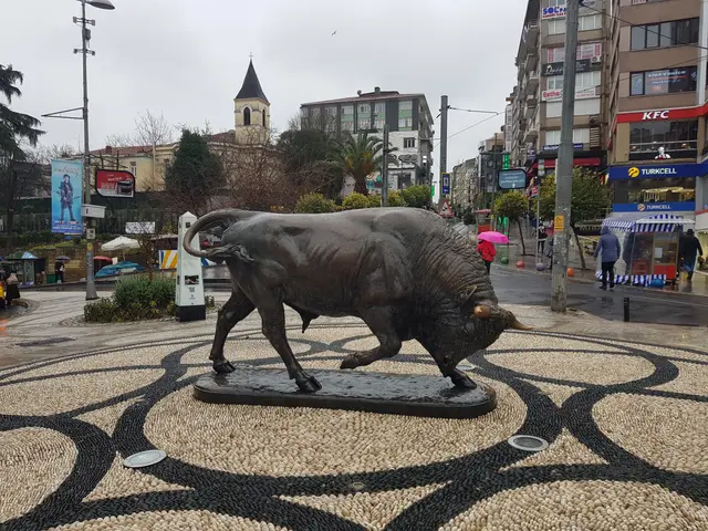 Kadıköy'de boğa heykeli; mozaik taş döşeli meydanda bronz boğa, arkada dükkânlar ve yürüyen insanlar.