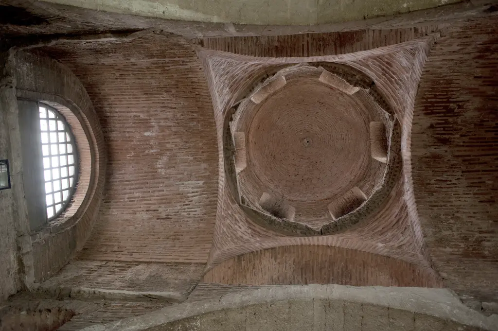 Fenari İsa Camii'nde kuzey kilisenin kubbesine dik yukarı bakış; tuğla örgülü kubbe, dört köşede pandantifler, kasnakta pencere nişleri ve solda yuvarlak pencere.