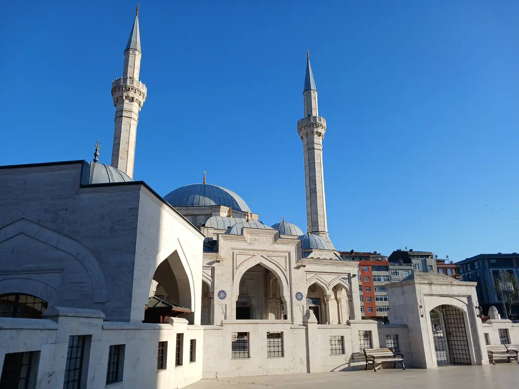 Seyyid Nizam Camii ve Külliyesi; iki ince minare, kubbeler, kemerli giriş revağı ve önündeki geniş merdivenli avlu.