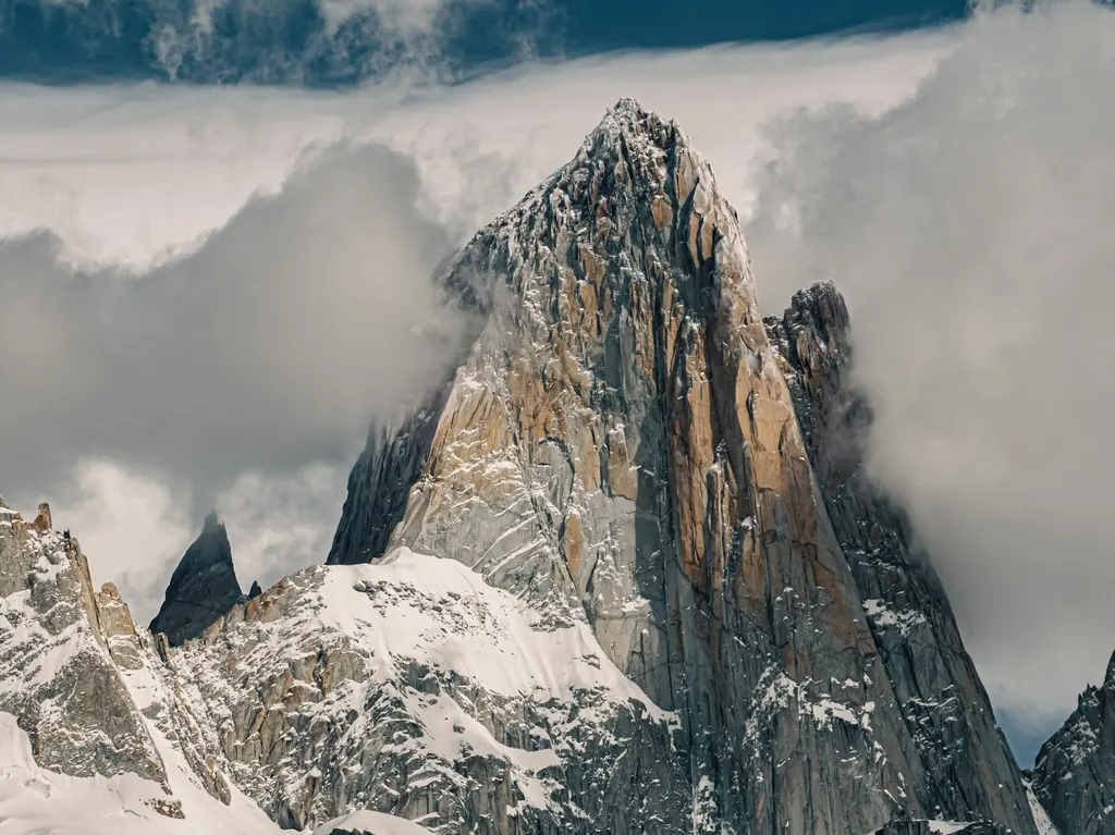 Patagonya'da Fitz Roy Dağı; sivri granit kuleleri, karlı yamaçları ve önündeki bozkır.