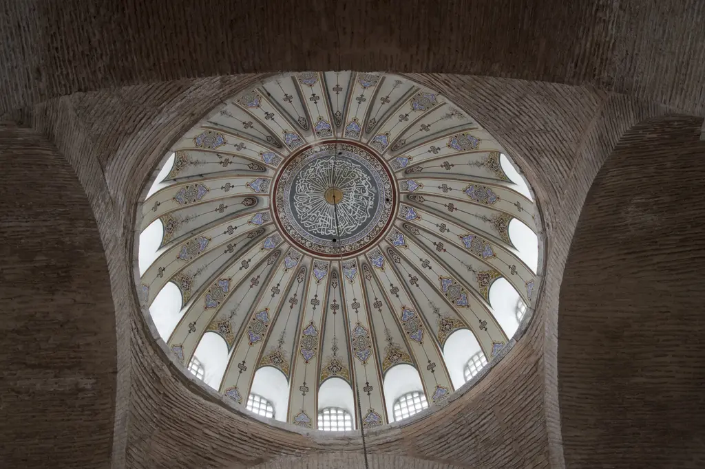 Kalenderhane Camii'nin kubbesi içten; pencereli kasnaktan açılan krem dilimler, mavi kırmızı motifler, ortada hat madalyonu ve tuğla pandantifler.