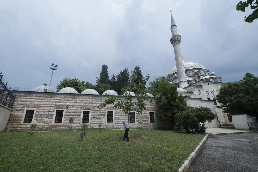 Güneyden Nişancı Mehmed Paşa Camii; önde çimenli bahçe, taş ve tuğla sıralı uzun avlu duvarı, üstünde küçük kubbeler ve arkada minare ile ana kubbe.