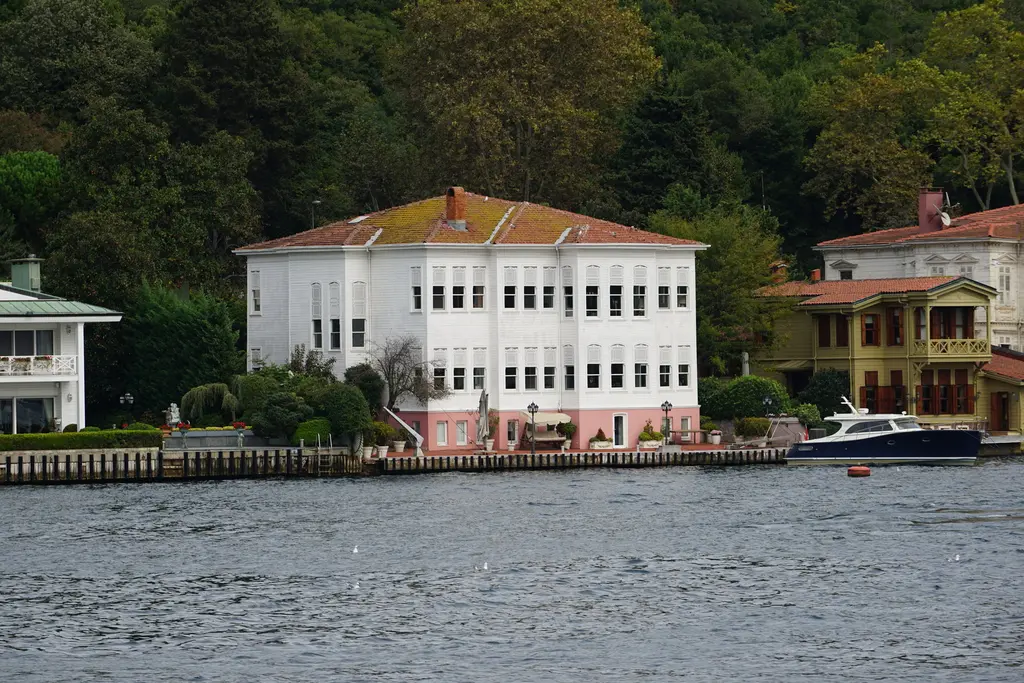 Yağlıkçı Hacı Raşid Bey Yalısı; beyaz ahşap cephe, kiremit çatı, yanında küçük yalı ve önde tekne.