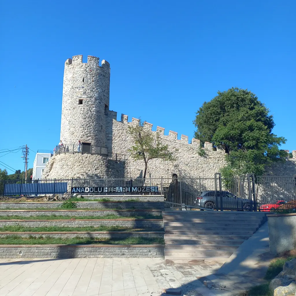 Anadolu Hisarı Müzesi'nin girişi; yuvarlak taş kule, mazgallı sur, müze tabelası ve önde basamaklı meydan.