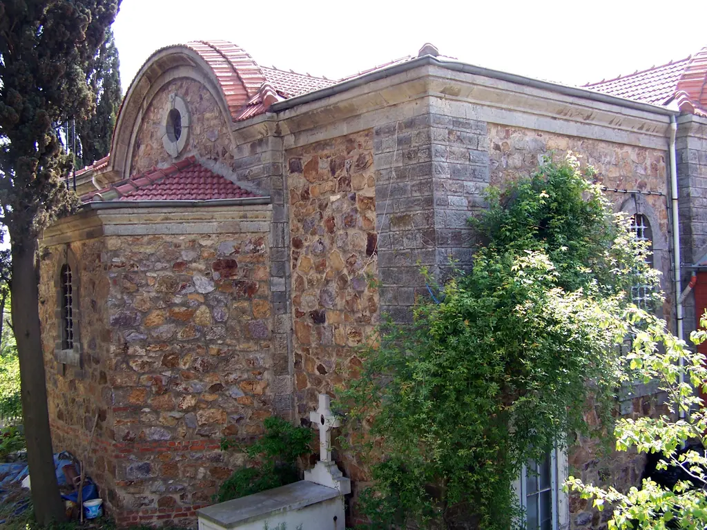 Aya Yorgi Manastırı'nda taş kilise; kesme taş duvarlar, kırmızı kiremitli çatı, sarmaşık ve önde mermer haç.