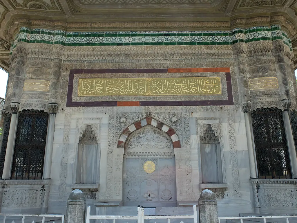 Çeşmenin kuzeybatı cephesi; kırmızı beyaz taşlı kemer, altında ayna taşı, üstte üç sıra hâlinde kitabe ve çini kuşağı.