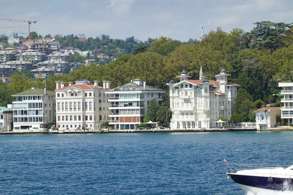 Boğaz'dan Afif Paşa Yalısı ve komşuları; kıyı boyunca beyaz yalılar, arkada ağaçlık sırt ve önde sürat teknesi.