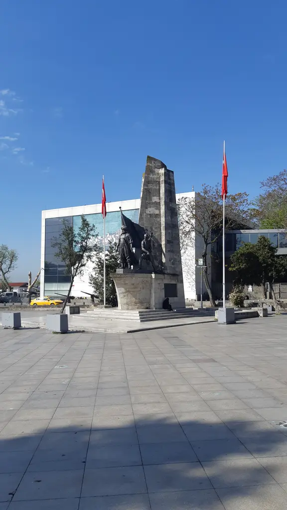 Barbaros Anıtı'nın bronz figürleri; aşağıdan bakışta kavuklu Barbaros, iki yanında levendler ve mavi gökyüzü.