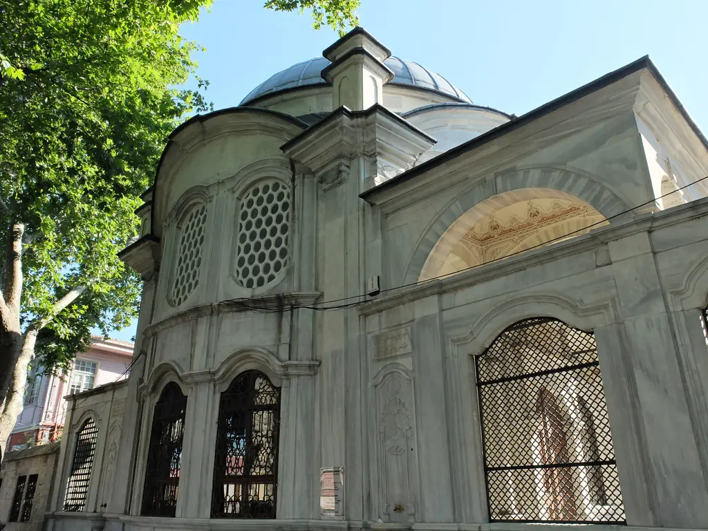 Şah Sultan Türbesi'nin caddeye bakan cephesi; kurşun kubbe, petekli oval pencereler ve demir şebekeli büyük pencere.