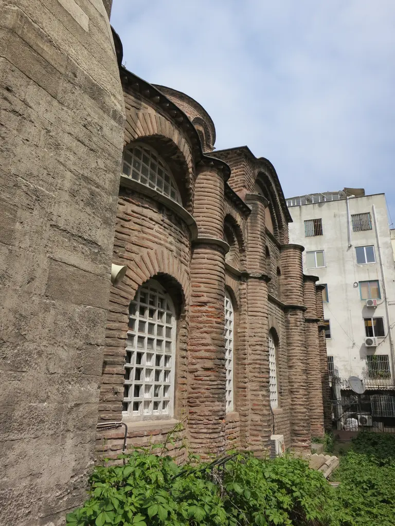 Bodrum Camii'nin güney cephesi dar açıdan; arka arkaya dizilen yarım daire gömme payandalar, kemerli kafesli pencereler, tuğla ve taş almaşık örgü, altta sarmaşık.
