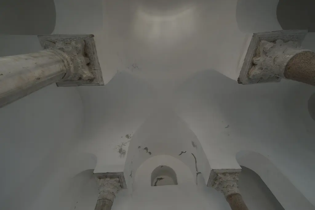 Bodrum Camii'nin alt yapısında dik yukarı bakış; dört devşirme başlıktan kalkan beyaz badanalı tonozlar, ortada kubbemsi örtü, köşelerde pembe granit sütun gövdeleri.