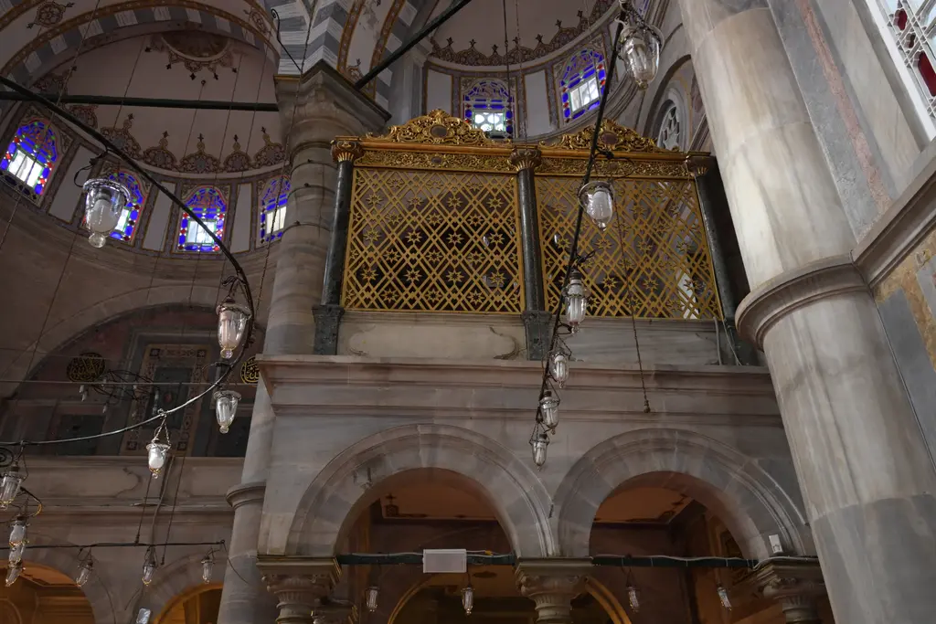 Laleli Camii'nde hünkâr mahfili; altın yaldızlı ahşap kafes, altında mermer sütunlar ve yuvarlak kemerler, yanda asılı kandiller.