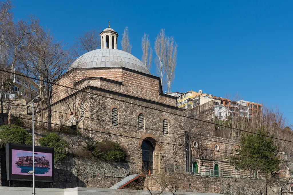 Tophane'de Tophane-i Âmire binası; kesme taş duvarlar, çatıda kurşun kaplı kubbeler ve önünde ağaçlı bir bahçe.