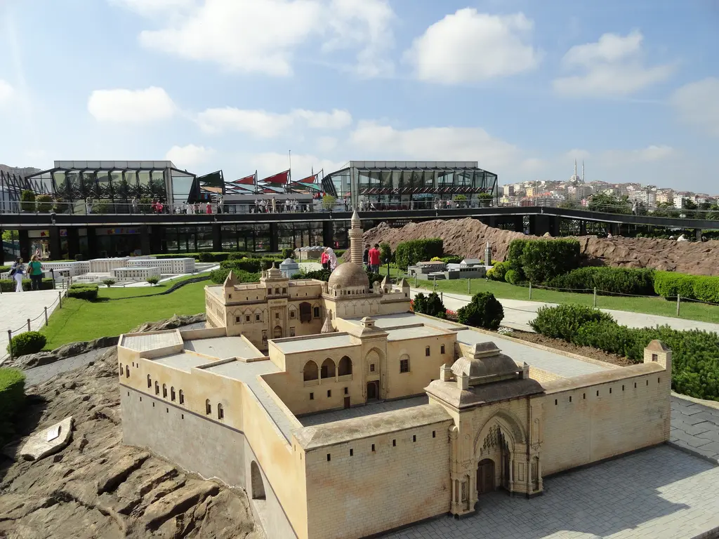 Miniatürk'te İshak Paşa Sarayı maketi; bej surlar, oymalı taç kapı ve kubbeli cami bölümü, yapay kayalık zemin, arkada cam bina.