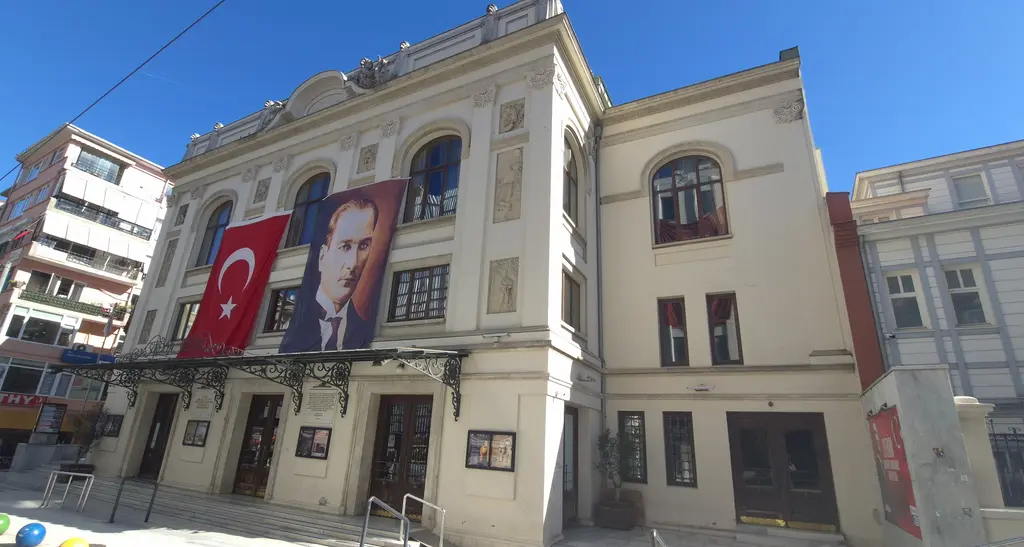 Süreyya Operası'nın cephesi; asılı Türk bayrağı ve Atatürk portresi, kemerli pencereler ve mavi gökyüzü.