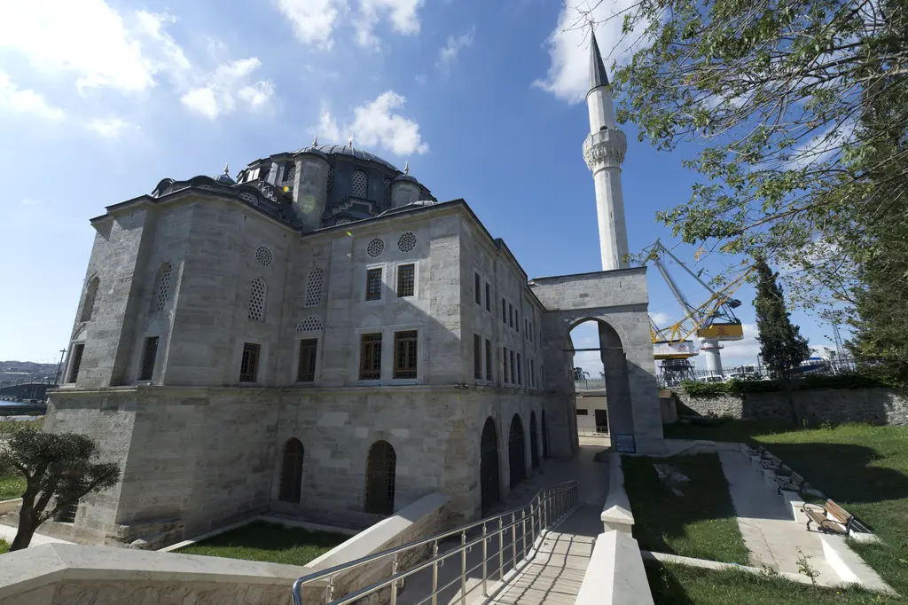 Azapkapı Sokullu Mehmed Paşa Camii; cami gövdesini minareye bağlayan yüksek sivri kemerli taş köprü, önde rampa ve çimenler.