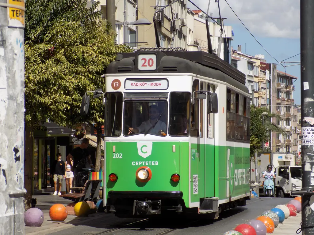 Kadıköy'de nostaljik tramvay; yeşil beyaz eski tramvay arabası, ray boyunca renkli toplar ve apartmanlar.
