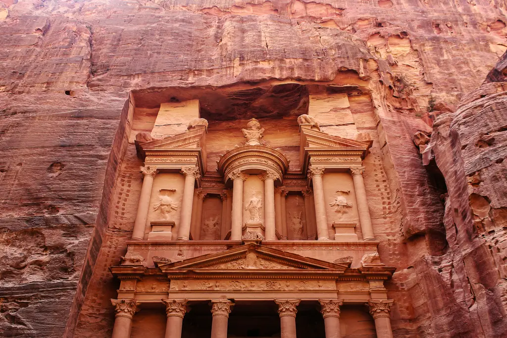 Petra'da kayaya oyulmuş Hazine cephesi; gül kırmızısı kumtaşına işlenmiş sütunlar, üçgen alınlık, ortadaki yuvarlak külah biçimli bölüm ve cepheyi çevreleyen doğal kaya duvarı.
