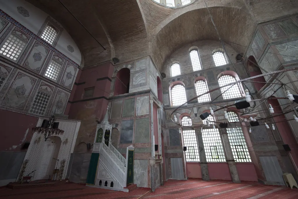 Kalenderhane Camii'nde harimin köşesi; beyaz geometrik oymalı mihrap, yeşil perdeli beyaz mermer minber, kalem işli duvar ve kemerli pencereler.