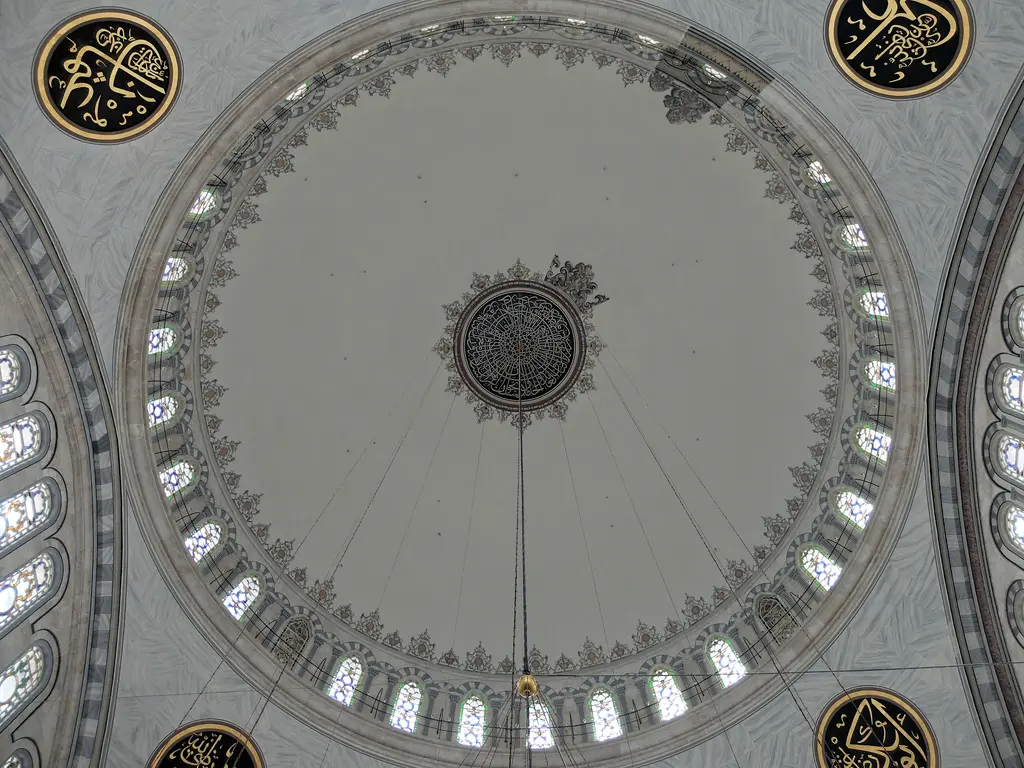 Nuruosmaniye Camii'nin kubbesi tam alttan; ortada madalyon, çepeçevre dizilen pencere halkası, pandantiflerde yaldızlı hat madalyonları ve gri beyaz mermer tonları.