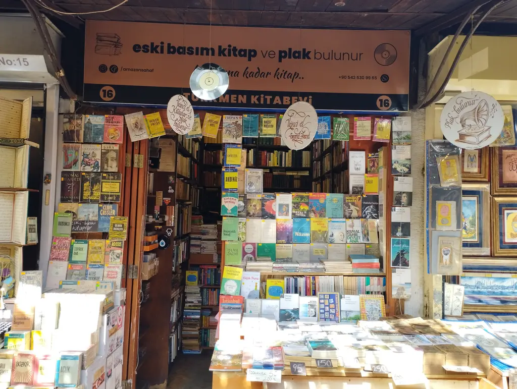 Sahaflar Çarşısı'nda eski basım kitap ve plak satan bir dükkân; siyah tabela, tavandan sarkan plaklar, sağda cam kapı, iki yanda eski ciltli kitap rafları ve önde açık sandıklar.