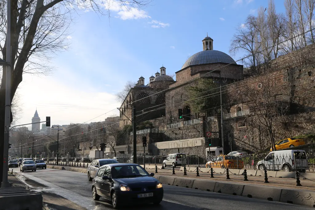 Tophane'de kıyı yolu; arabaların geçtiği cadde, sağda yamaca oturan kubbeli taş bina ve uzakta Galata Kulesi.