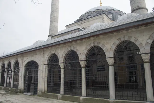 Üsküdar'da Atik Valide Camii; demir parmaklıklı kemerli dış revak, arkasında kurşun kubbe ve iki minare.