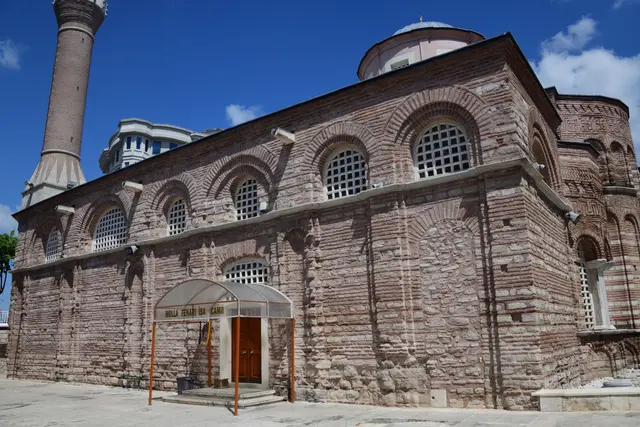 Fatih'te Fenari İsa Camii'nin güney cephesi; iki sıra kemerli şebekeli pencere, tuğla ile taşın almaşık örgüsü, solda tuğla minare ve sağda pembe kasnaklı kubbe.