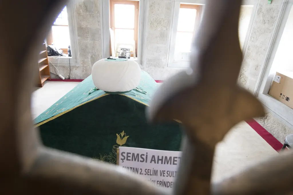 Şemsi Paşa Camii'nde bronz şebekenin arasından görülen yeşil örtülü sanduka ve beyaz sarık.