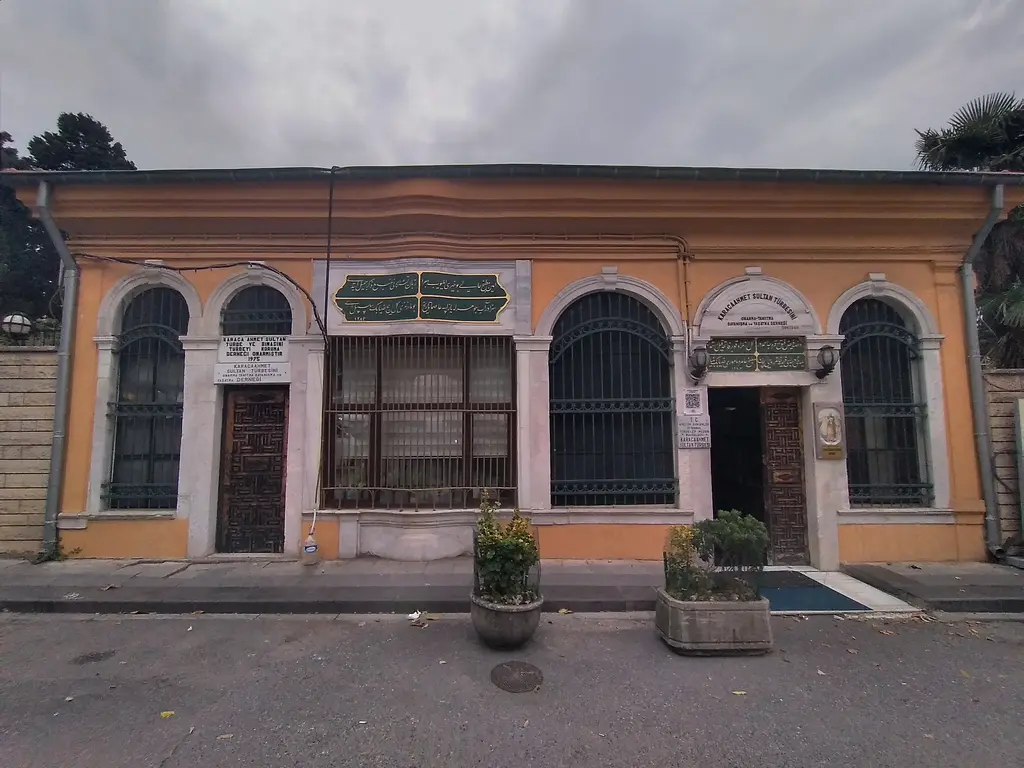 Üsküdar'da Karaca Ahmed Sultan Türbesi; turuncu cepheli tek katlı yapı, kemerli parmaklıklı pencereler ve yeşil levhalar.