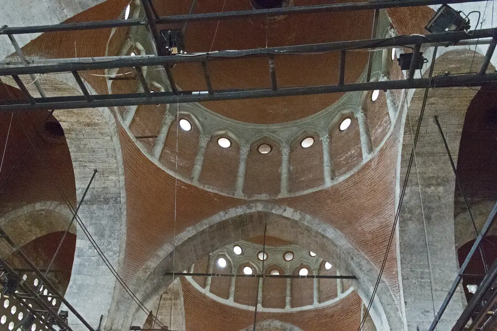 Tophane-i Âmire'de iç içe kubbeler ve kemerler; kasnaklarda yuvarlak pencereler, önde sergi ışıkları için kurulmuş metal iskelet.