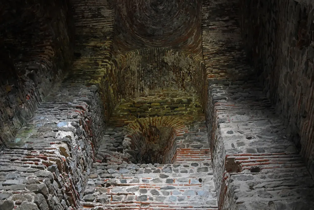 Yoros Kalesi'nin kuzey kapı kulesinin içi; taş ve tuğla duvarlar, basamaklar ve yukarıda yosunlu tonoz.