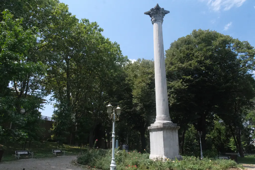 Gülhane Parkı'nda Gotlar Sütunu; yüksek kaide üstünde beyaz mermer gövde, Korint başlık, çevresinde yeşil ağaçlar, lamba direği ve mavi gök.